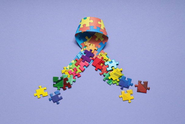 Szalag többszínű kirakós darabokkal, könnyű háttérrel. Az autizmus világnapja koncepció - Fotó, kép