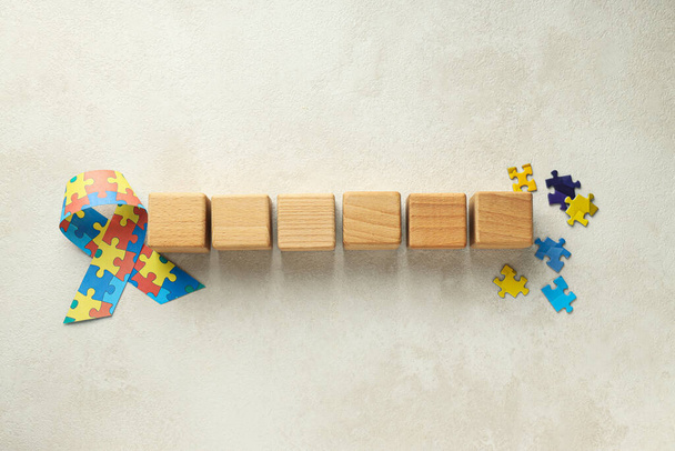 Stuha s barevnými puzzle kousky a dřevěné kostky na světlém pozadí. Koncept Světového dne autismu - Fotografie, Obrázek