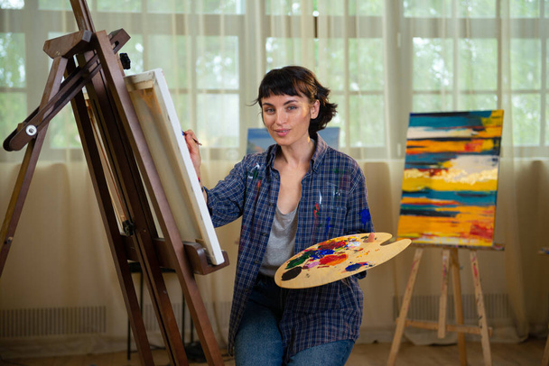 female painter painting on canvas in her workshop. - Valokuva, kuva