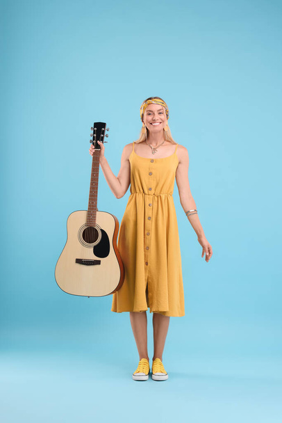 Happy hippie woman with guitar on light blue background - 写真・画像