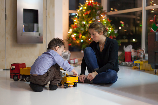 Mãe e pequeno filho brincando com carro de brinquedo no dia de Natal
 - Foto, Imagem