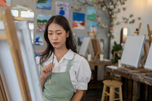 Ázsiai nő festi a művészetet. Ő egy profi művész. Az akvarellfestő papírra festi a művészetet. Szabadúszó művész festékek akvarell. Kreatív művészeti munka akvarellel. Művészeti rajz ötletek. - Fotó, kép