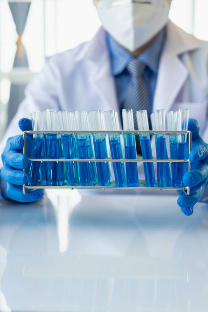 Vědci, vědci pracují in vitro analýzou s modrými kapalinami v chemických laboratořích nebo experimentální technice, lékařské biologii. Vzdálený obrázek svisle - Fotografie, Obrázek