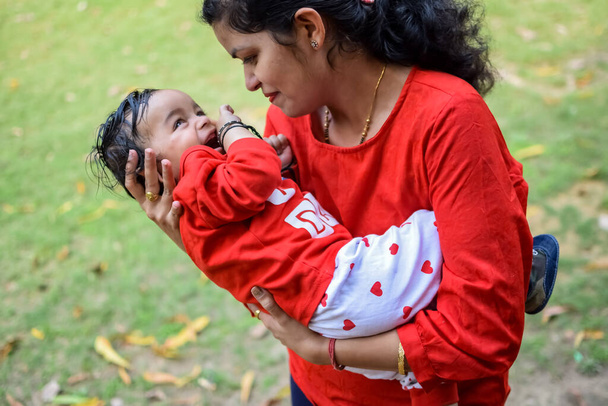 社会公園で赤ちゃんを運ぶ愛するお母さん。彼女の手の中に幸せな母親の子供を保持の明るい肖像画。母親抱擁彼女の小さな9ヶ月息子. - 写真・画像