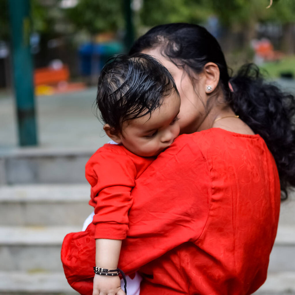 社会公園で赤ちゃんを運ぶ愛するお母さん。彼女の手の中に幸せな母親の子供を保持の明るい肖像画。母親抱擁彼女の小さな9ヶ月息子. - 写真・画像