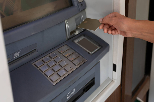 жіноча рука тягне кредитну картку в банкомат. - Фото, зображення