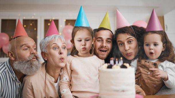 Happy birthday, gift and big family blowing candles with cake in a home party, event and celebration together. Mother, father and grandparents excited for surprise gathering with children or kids. - Photo, Image