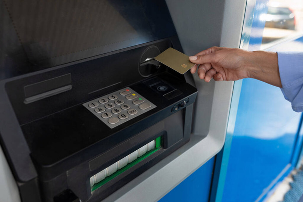 жіноча рука кладе банківську картку в банкомат. - Фото, зображення