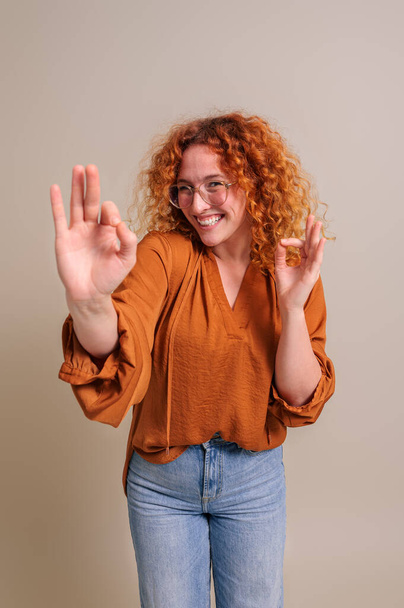 Izgalmas női szabadúszó vörös hajú mutatja OK gesztus közben áll a háttérben - Fotó, kép