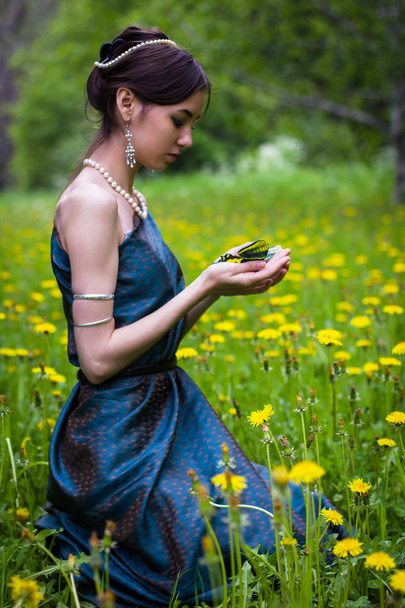 the girl in the dandelions holding a butterfly - Фото, зображення