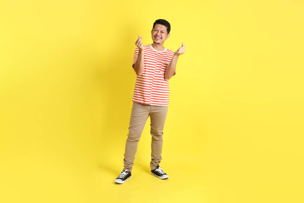 The adult Asian man in casual clothes standing on the yellow background. - Foto, Imagem