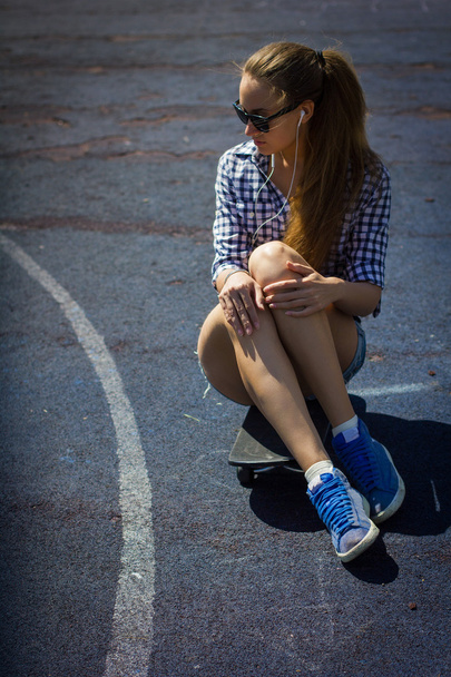 cute girl in shorts with a skateboard on the Playground - Foto, afbeelding