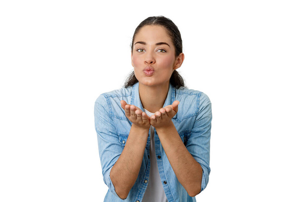 brunette woman looking straight ahead with her hands close to her face blowing a kiss isolated on a white background - Photo, Image