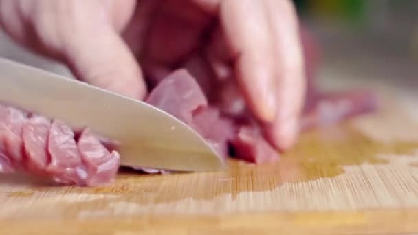 Een man in de keuken snijdt vers vlees met een mes. Het eten wordt klaargemaakt voor een nieuw gerecht voor het diner. - Video