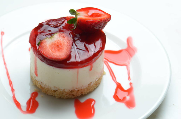 Cheesecake covered with a layer of strawberry gelatin and garnished with a strawberry. - Photo, Image