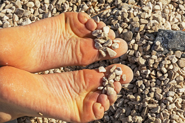 exercícios terapêuticos de pernas de crianças de pernas chatas em uma praia com pequenos seixos. prevenção de valgo e pés chatos em crianças - Foto, Imagem