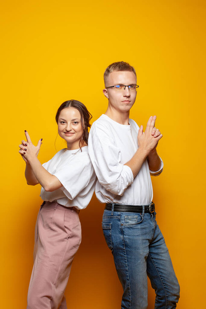 Funny couple woman and man posing against bright orange studio wall background - Photo, Image