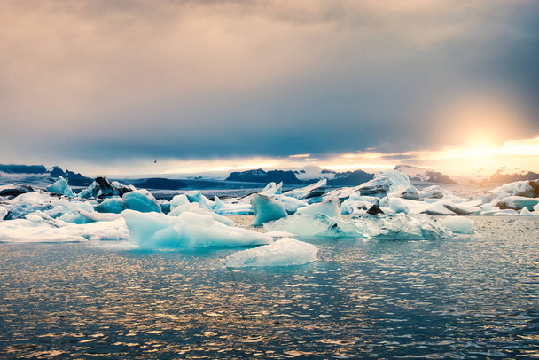 Hermoso paisaje de puesta de sol que brilla sobre la laguna glaciar de Jokulsarlon con iceberg azul que se derrite durante el verano en el parque nacional de Vatnajokull en Islandia - Foto, Imagen