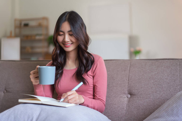 Nők szabadidő kanapén kávézni és jegyzeteket írni napló notebook életmód otthon. - Fotó, kép
