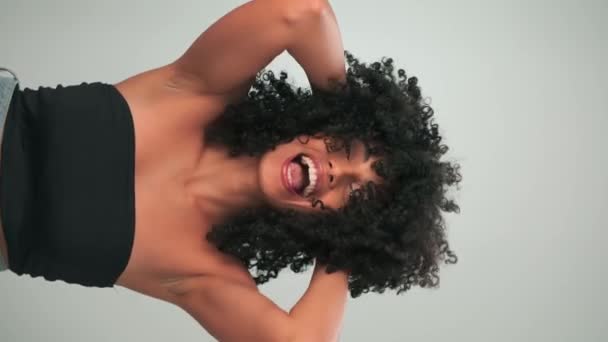 Függőleges portré fiatal mosolygós modell göndör haj afro stílus és fényes smink. Lassú mozgás, közelkép. - Felvétel, videó