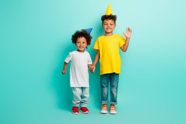 Ganzkörperfoto von niedlichen zwei kleinen Jungen winken Handfläche halten Hände Geburtstagsparty gekleidet stilvolle Kleidung isoliert auf cyanfarbenem Hintergrund. - Foto, Bild