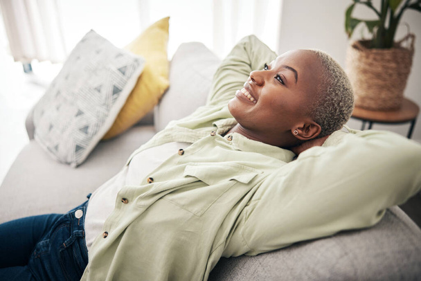 Mujer africana, relajarse y la calma estirándose en el sofá en casa, sala de estar y salón con paz, felicidad y descanso en fin de semana. Feliz, cara y mentalidad de libertad en casa nueva o apartamento con propietario. - Foto, Imagen