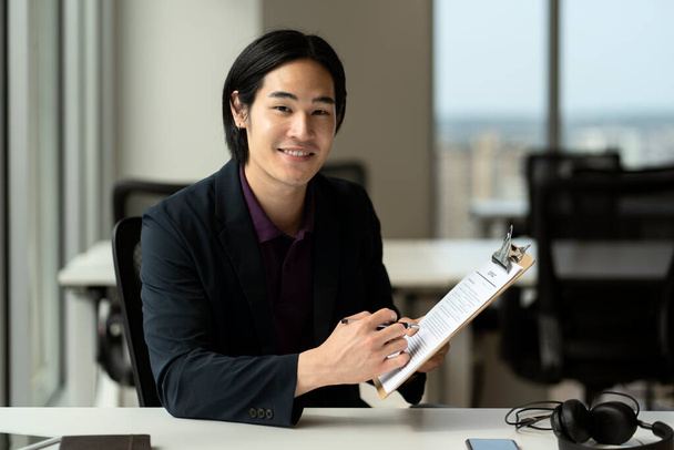 Handsome smiling asian man, manager, entrepreneur reading contract, sings documents working in modern office. Successful business, career  - Fotografie, Obrázek