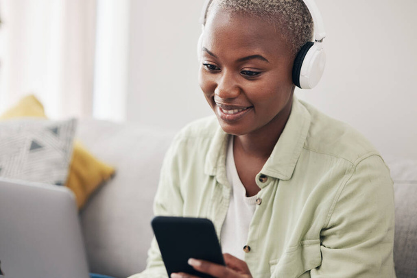 Αρχική σελίδα, ακουστικά ή μαύρη γυναίκα με τηλέφωνο ή φορητό υπολογιστή για τα μέσα κοινωνικής δικτύωσης, μήνυμα ή σε απευθείας σύνδεση συνομιλία. Χαμόγελο, ειδοποίηση ειδοποίησης ή αφρικανικό πρόσωπο streaming μουσικής σε mobile app στην ιστοσελίδα ή το δίκτυο στο σπίτι. - Φωτογραφία, εικόνα
