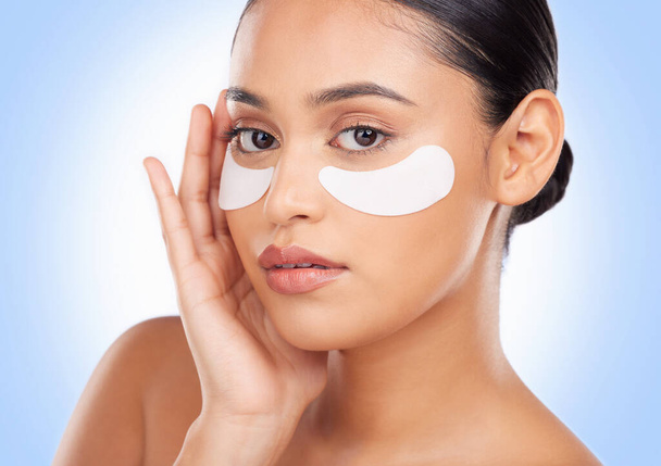 Portrait, skincare and eye mask with a natural woman in studio on a blue background for antiaging treatment. Face, beauty and wellness product with a young model at the salon for a facial application. - Photo, Image