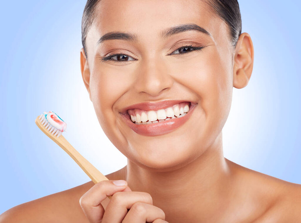 Retrato feliz, mulher e escova de dentes em fundo azul para limpeza dental, gengivite e beleza em estúdio. Modelo, pasta de dentes e escovação de dentes com bambu para higiene oral, sorriso saudável e cuidados. - Foto, Imagem