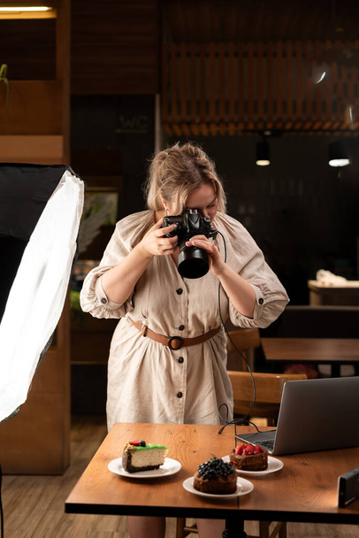 Jovem fotógrafa usando sua câmera profissional para tirar fotos no café de alimentos de padaria. Espaço de cópia - Foto, Imagem