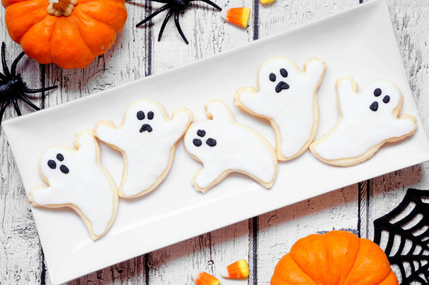 Plate of Halloween ghost cookies. Above view table scene on a white wood background. - Photo, Image