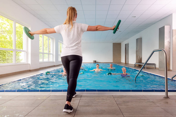 Mujeres y hombres durante la clase de entrenamiento en gimnasia acuática en un gimnasio de rehabilitación - Foto, Imagen