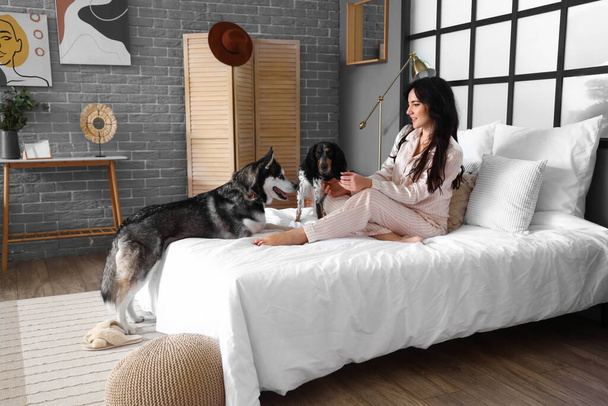 Młoda kobieta z uroczymi psami w sypialni - Zdjęcie, obraz