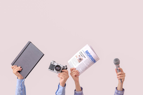 Frauenhände mit Notizbuch, Zeitung, Fotokamera und Mikrofon auf hellem Hintergrund - Foto, Bild
