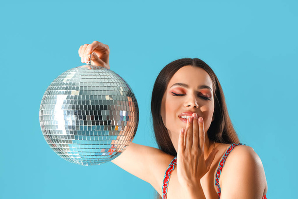 Gyönyörű fiatal nő disco labda kék háttér, közelkép - Fotó, kép