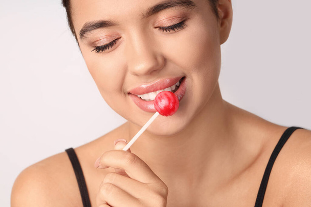Young woman with beautiful lips and lollipop on light background, closeup - Photo, Image