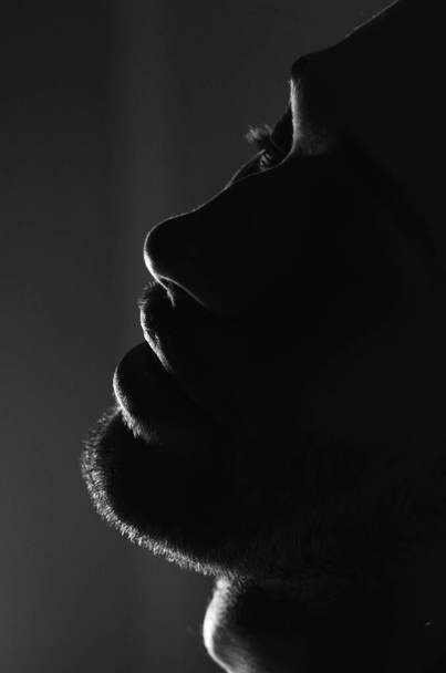 La silueta de un hombre sin afeitar la cara. Labios, nariz, ojos. Foto monocromática. Retrato de perfil masculino joven - Foto, Imagen