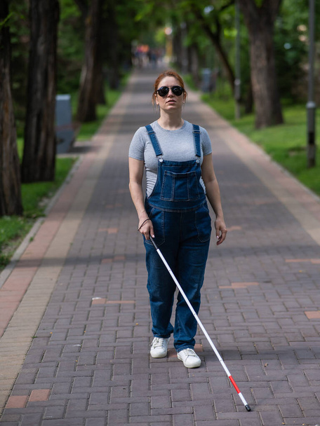 Blind pregnant woman walking in the park with a cane - Photo, image