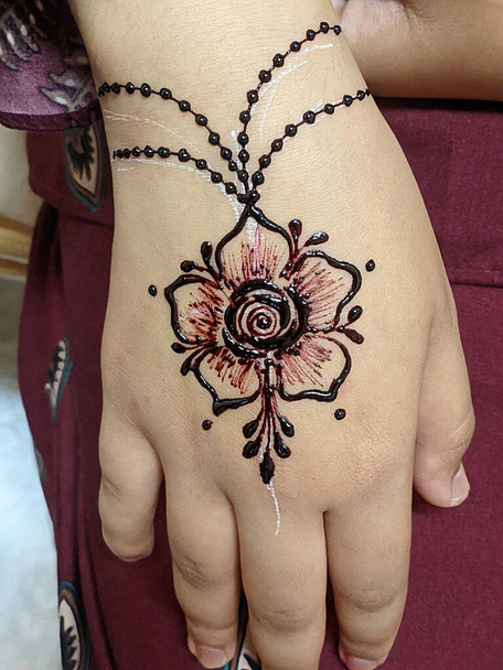Een hand versierd met ingewikkelde henna ontwerpen, wervelende patronen in rood-bruin, het creëren van een boeiende en tijdelijke kunstwerk. Selectieve aandachtspunten - Foto, afbeelding