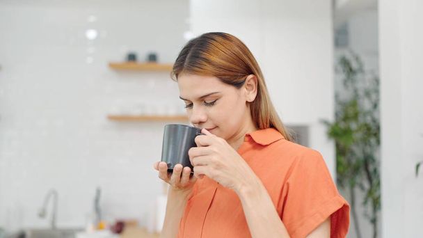Onnellinen nainen rentoutuu kuumalla kahvilla aamulla kotona viikonloppuna. Rento nainen haistaa kahvin. Nainen nauttii aamiaisesta kahvin kanssa. Elämäntapakäsite - Valokuva, kuva