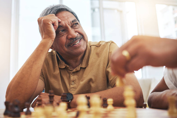 Senior man, home and chess for competition, game and strategy with friend for focus and relax in living room. Thinking, elderly and person with board for challenge, planning and mindset in house. - Photo, Image