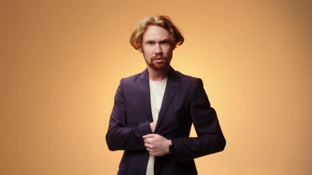 Handsome unshaven bearded young guy in a business suit, isolated on a yellow background in the studio. People sincere emotions, lifestyle concept. - Footage, Video
