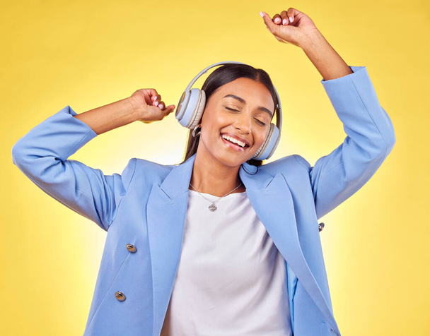 Dancing, fashion or happy woman streaming music in headphones on yellow background. Relax, smile or calm entrepreneur listening to radio song, album or audio sound on subscription playlist in studio. - Zdjęcie, obraz