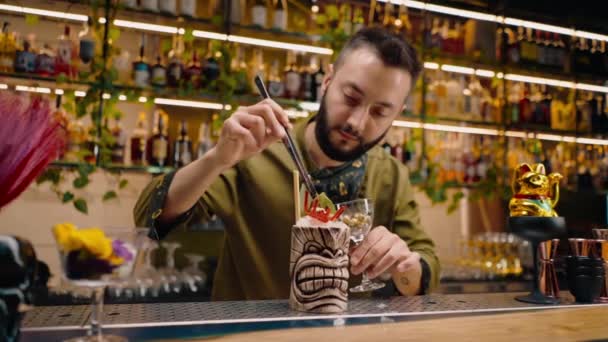 un barista in un bar o ristorante decora un cocktail alcolico appena preparato con pinze - Filmati, video