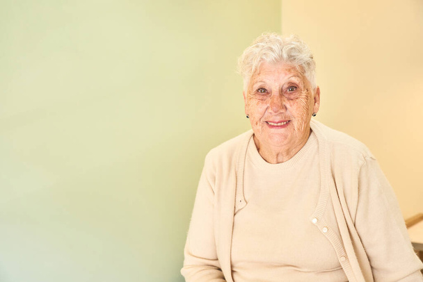 Πορτρέτο με αντίγραφο χώρου μιας ηλικιωμένης ευτυχισμένης γυναίκας χαμογελώντας στην κάμερα που κάθεται σε μια κλινική - Φωτογραφία, εικόνα