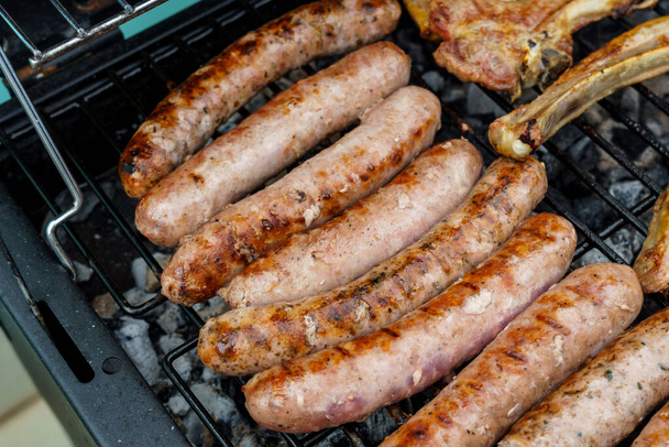 Flame-grilled sausages on a barbecue grill, appetizing and mouthwatering. - Photo, Image