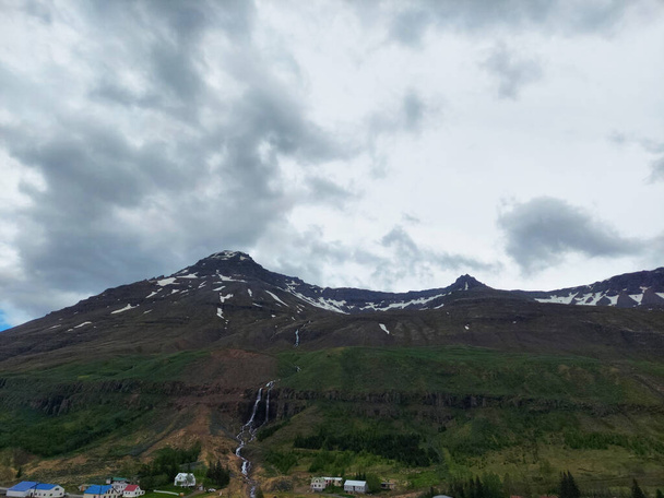 Naturaleza escénica Majestuosa Cordillera en Seyisfjrur, Islandia con Nubes y Reflexión en el Agua - Foto, imagen