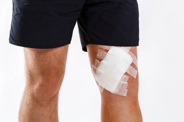 młody człowiek z bandaż elastyczny na kolana, na białym tle - Zdjęcie, obraz