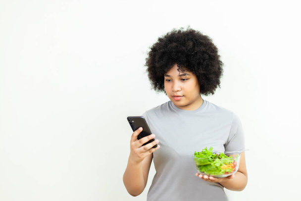 woman hair afro or fluffy using smartphone and holding salad vegetables. Female and healthy food diet. Want to lose weight. Eat healthy diet. Choose vegetable salad menu. Food full of benefits. - Fotó, kép